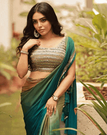 a woman wearing a blue and green saree with a silver blouse