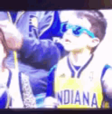 a young boy wearing sunglasses is wearing a yellow indiana jersey