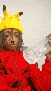 a man wearing a yellow pikachu hat is holding a bottle of water