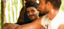 a group of young men are standing next to each other in a forest and smiling .