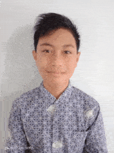 a young boy wearing a blue shirt with a white pattern is smiling for the camera