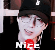 a man wearing glasses and a hat with the letter b on it is smiling and holding a microphone .