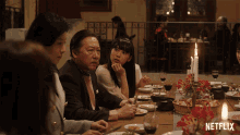 a group of people sitting at a table with a netflix logo