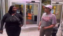 two women are standing next to each other in front of a store .