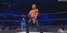a wrestler is dancing in a wrestling ring in front of a crowd of people .
