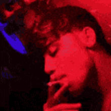 a man is sleeping in a dark room with a red light shining on his face .