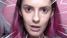 a woman with pink hair is making a funny face in front of a pink background .