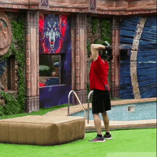 a man in a red shirt is holding a dumbbell in front of a painting of a wolf