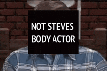 a man in a plaid shirt is behind a black sign that says not steves body actor