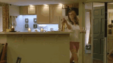a woman is standing in a kitchen holding a bottle of wine