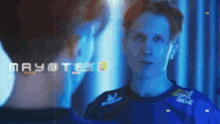 a man in a blue shirt is looking at his reflection in a mirror