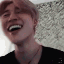 a close up of a person 's face laughing with their eyes closed .
