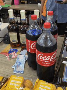 a bottle of coca cola sits on a counter next to a bottle of alcohol