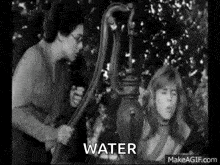 a black and white photo of a woman pumping water from a water pump .