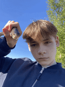 a young boy in a blue jacket is holding a fish