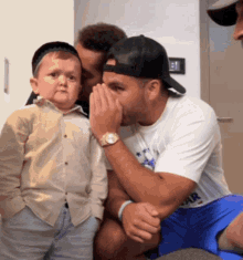 a man covering his mouth with his hands while a small boy looks on