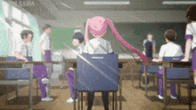 a girl with pink hair sits at a desk in a classroom with the word sama on the bottom left