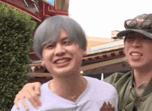 a man wearing sunglasses and a hat is standing next to another man with his arm around his shoulder