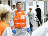 a man wearing an orange vest that says " tampon emergency "