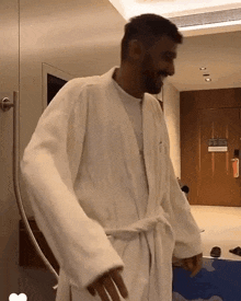 a man in a white robe is standing in a bathroom
