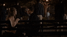 a man and a woman are sitting on a bench talking to each other