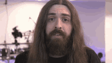 a man with long hair and a beard is making a funny face