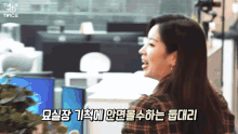 a woman in a plaid shirt is standing in front of a computer monitor and says twice in korean