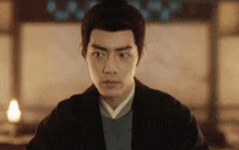 a man in a black jacket is looking at the camera .