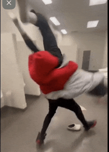 a person in a red jacket is doing a handstand in a room