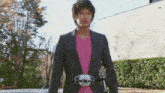a man wearing a pink shirt and a black suit has a belt that says ' akira ' on it