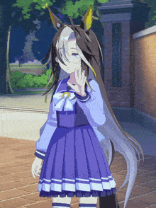 a girl in a blue dress is standing in front of a brick wall with chinese characters on it