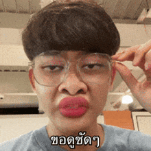 a man wearing glasses and making a funny face has a foreign language written on his shirt