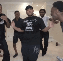 a group of men are dancing and one of them is wearing an intrepid t-shirt