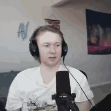 a man wearing headphones and a white shirt is sitting in front of a microphone .