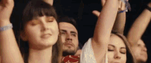 a group of people are dancing with their arms in the air at a concert .
