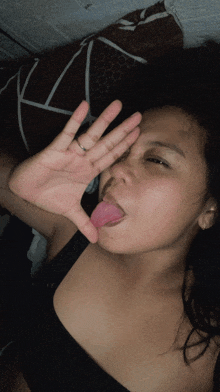 a woman sticking her tongue out while covering her face with her hand