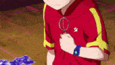 a young boy wearing a red shirt and a blue watch is holding a key chain .