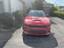 a red dodge charger is parked in a driveway next to a house