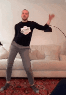 a man is dancing in front of a couch in a living room