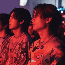 a man wearing a spongebob shirt sits next to another man in a dark room