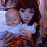 a woman is holding a baby in her arms and the baby is wearing a blue shirt that says ' silly '