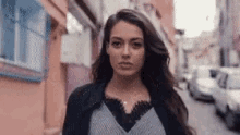 a woman is walking down a street with cars parked on the side