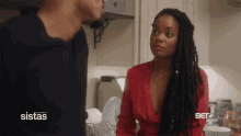 a woman in a red top is talking to a man in a kitchen with a bet logo on the bottom