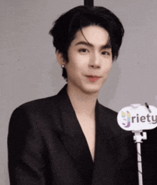 a man in a black suit is standing in front of a sign that says riety