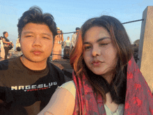 a man wearing a black shirt with the word mage on it poses with a woman