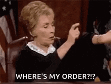 a judge is sitting at a table in a courtroom and pointing at a person .