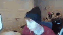a person wearing a black beanie is sitting in front of a computer screen .