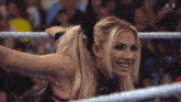 a woman is smiling in a wrestling ring while holding a microphone .