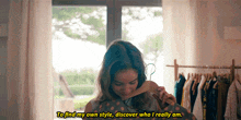 a woman is holding a hanger in front of a window and says " to find my own style discover who i really am "
