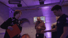 a man in a yamaha shirt talks to another man in a room